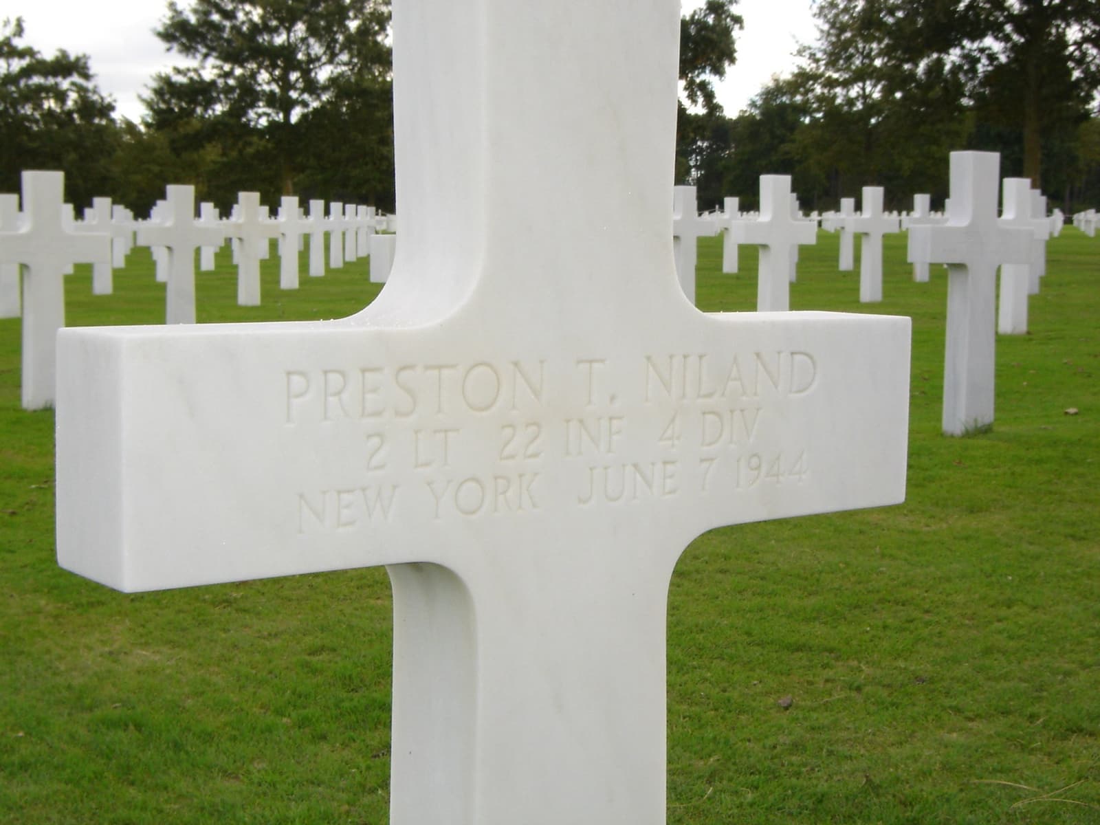 A white marble cross engraved Preston T. Niland, other crosses behind