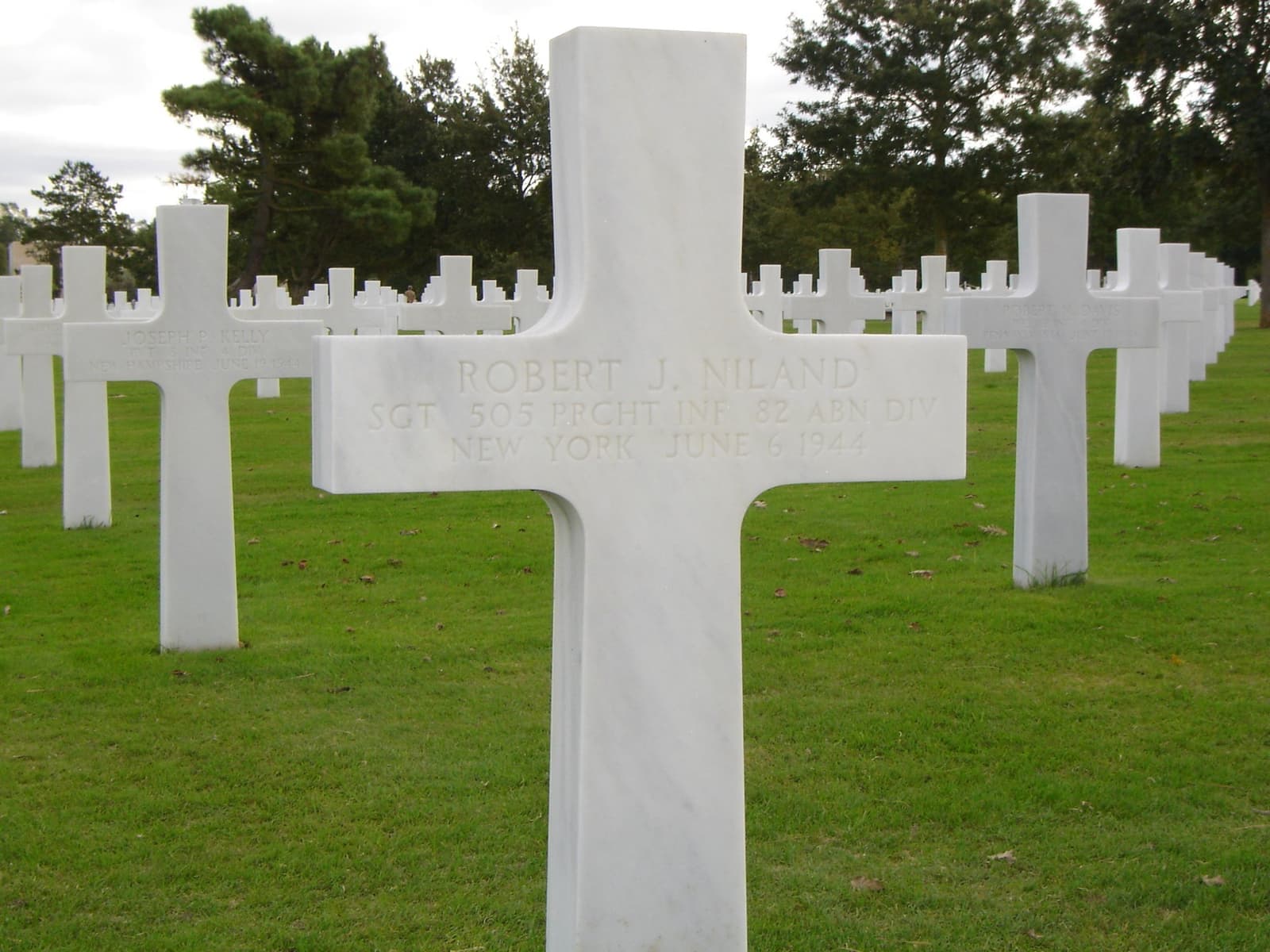 A white marble cross in a row of crosses on a lawn