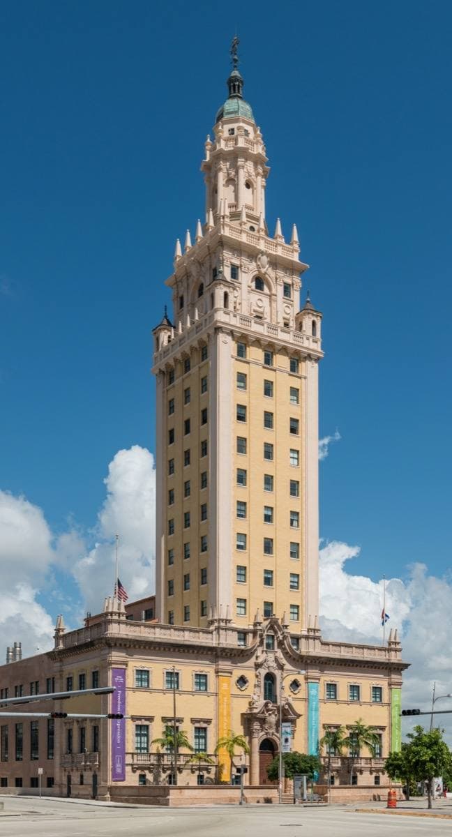 A cream Spanish-style tower with a domed cupola against a blue sky