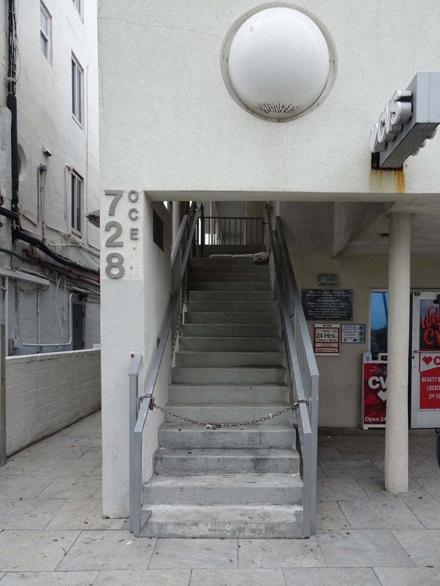 A narrow concrete staircase between white walls, the number 728 painted vertically beside it