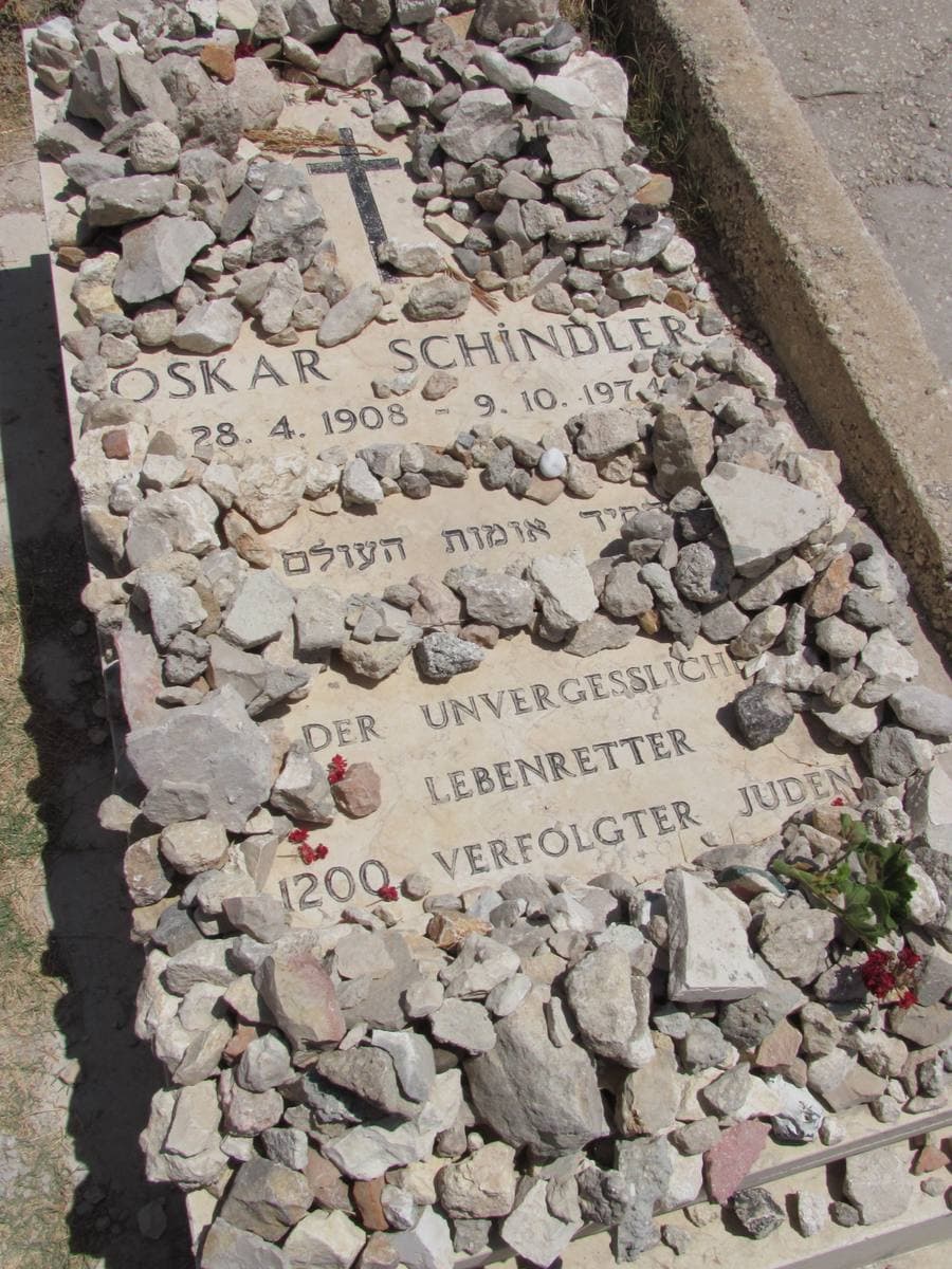 A pale stone grave slab seen from above, heaped with small stones