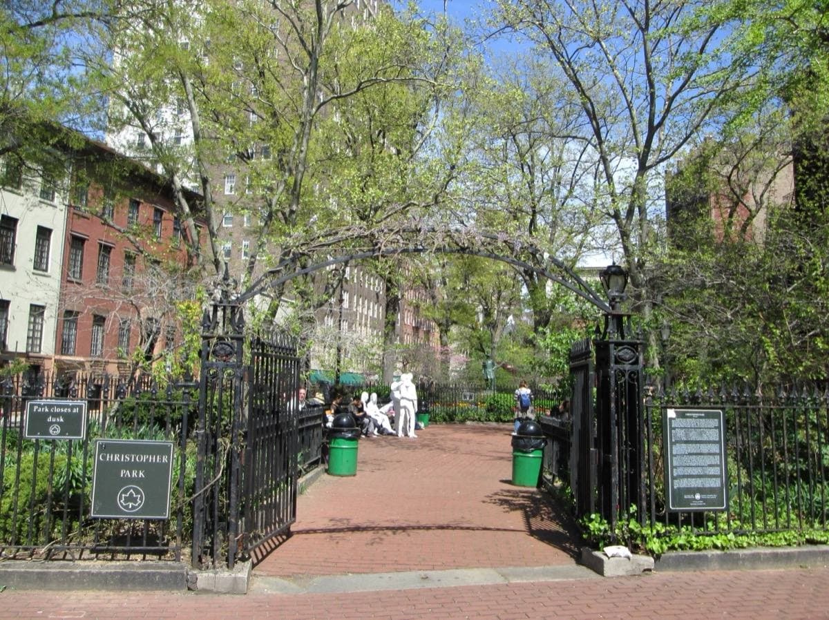 A small fenced park with a gate and trees