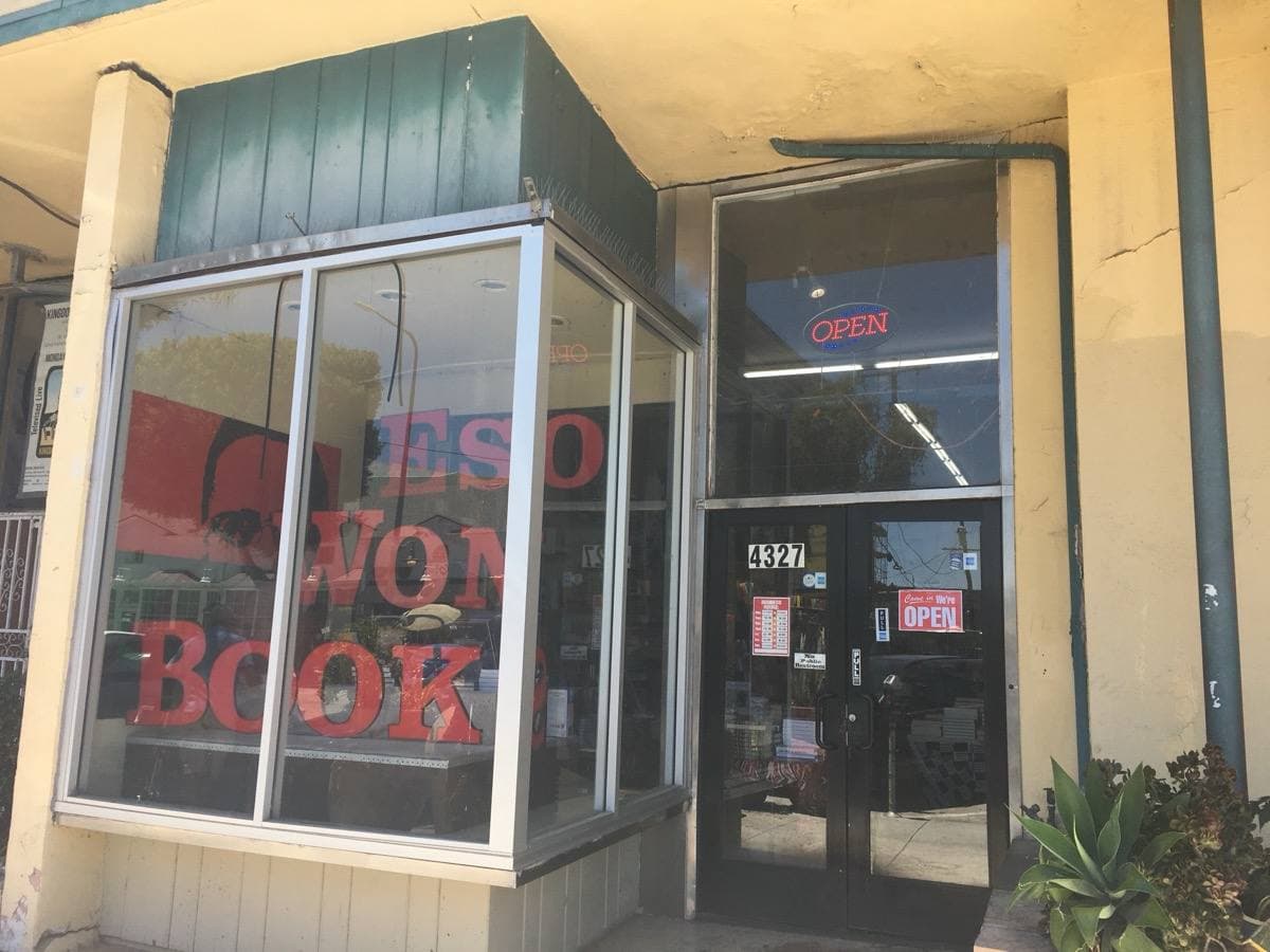 A corner shopfront with large windows and red lettering on the glass