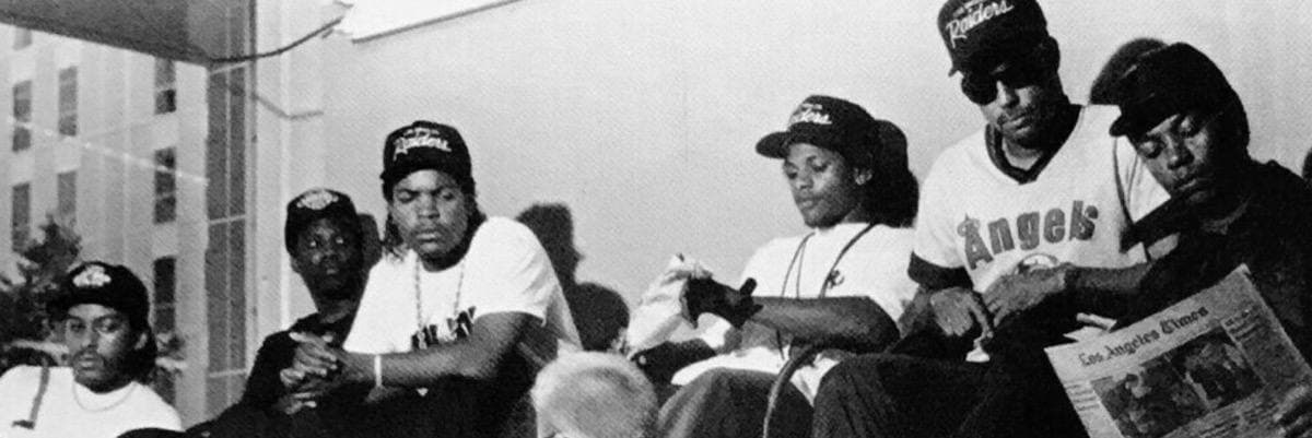 A wide black-and-white crop of six young men in caps, side by side