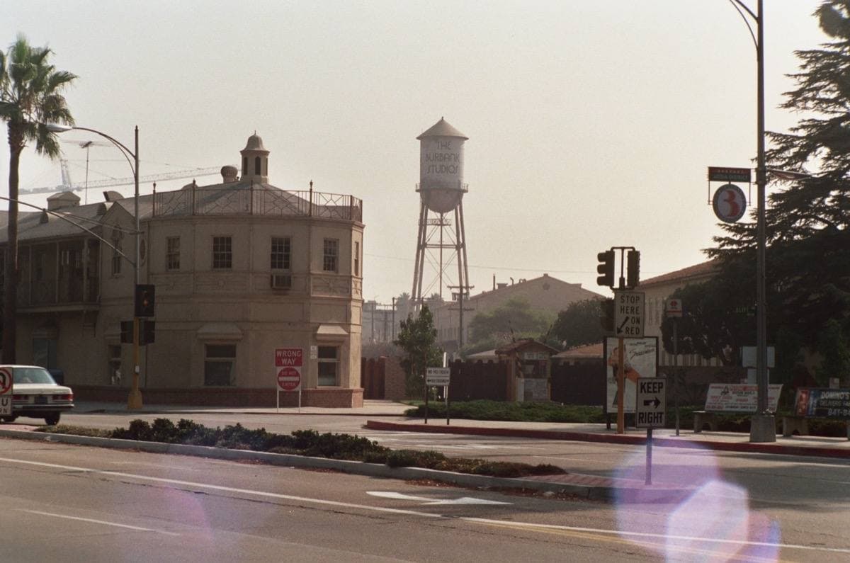 A street corner with an old studio building and a water tower behind it on a hazy day