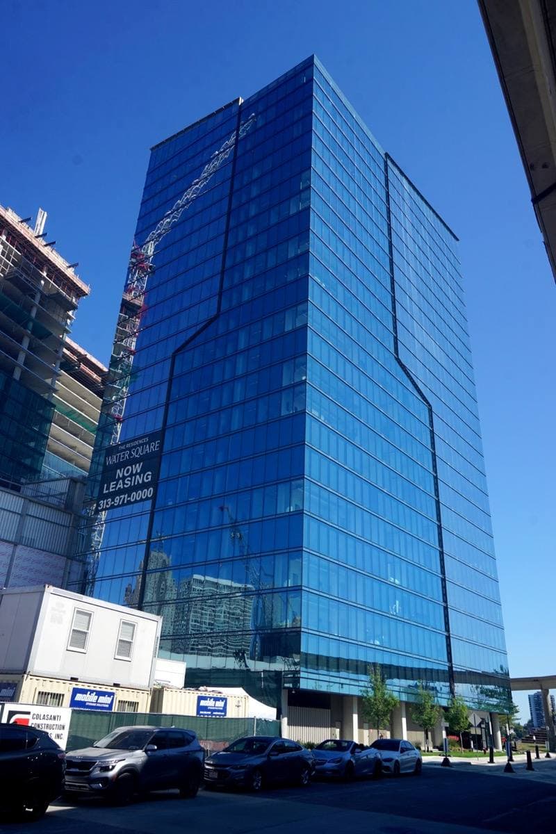 A tall blue glass residential tower against a clear sky