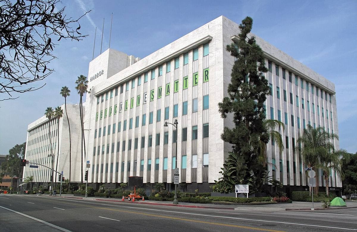 A long white six-storey office block with ribbon windows on a wide boulevard