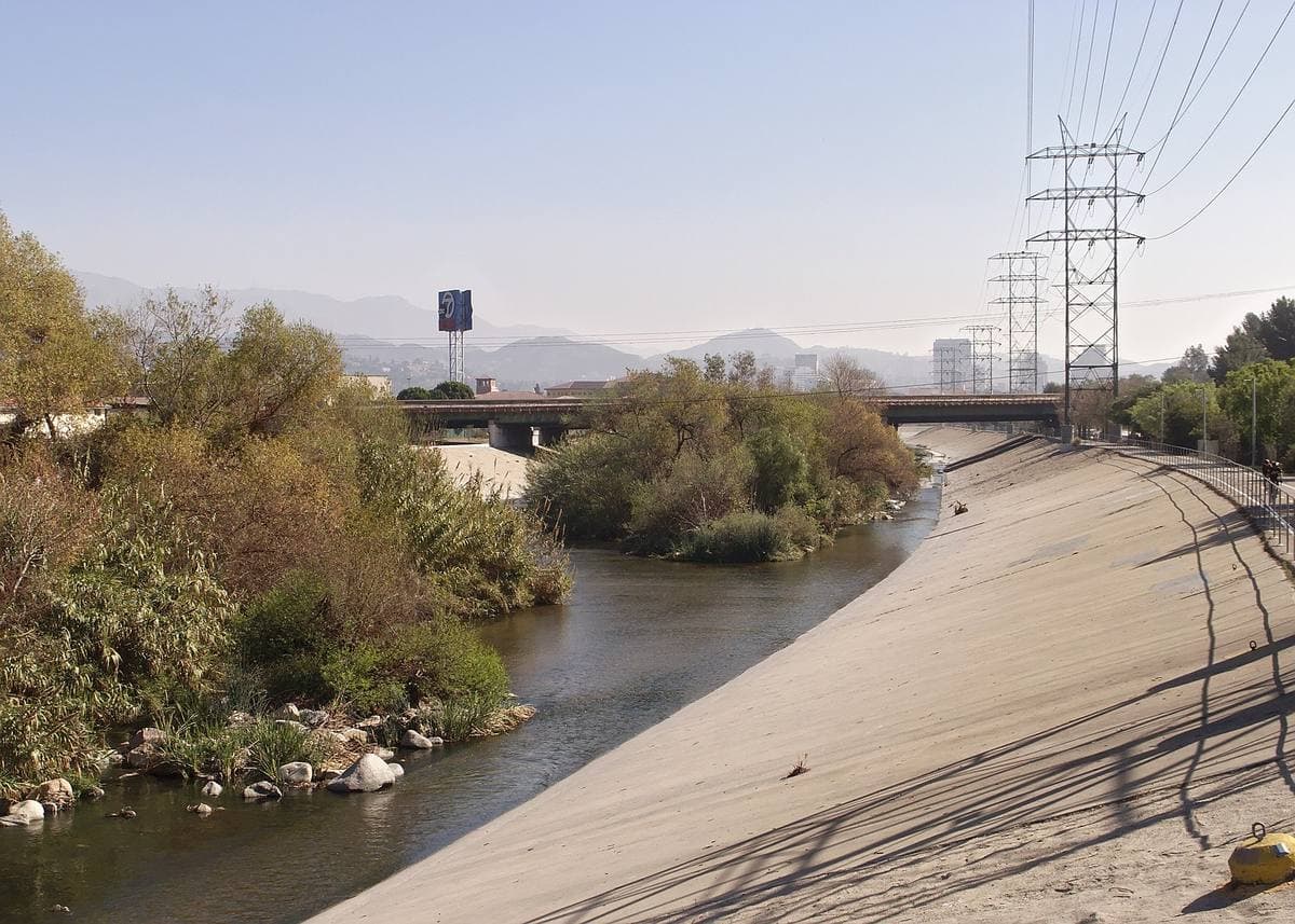 The concrete Los Angeles River channel with a bike path and hills beyond