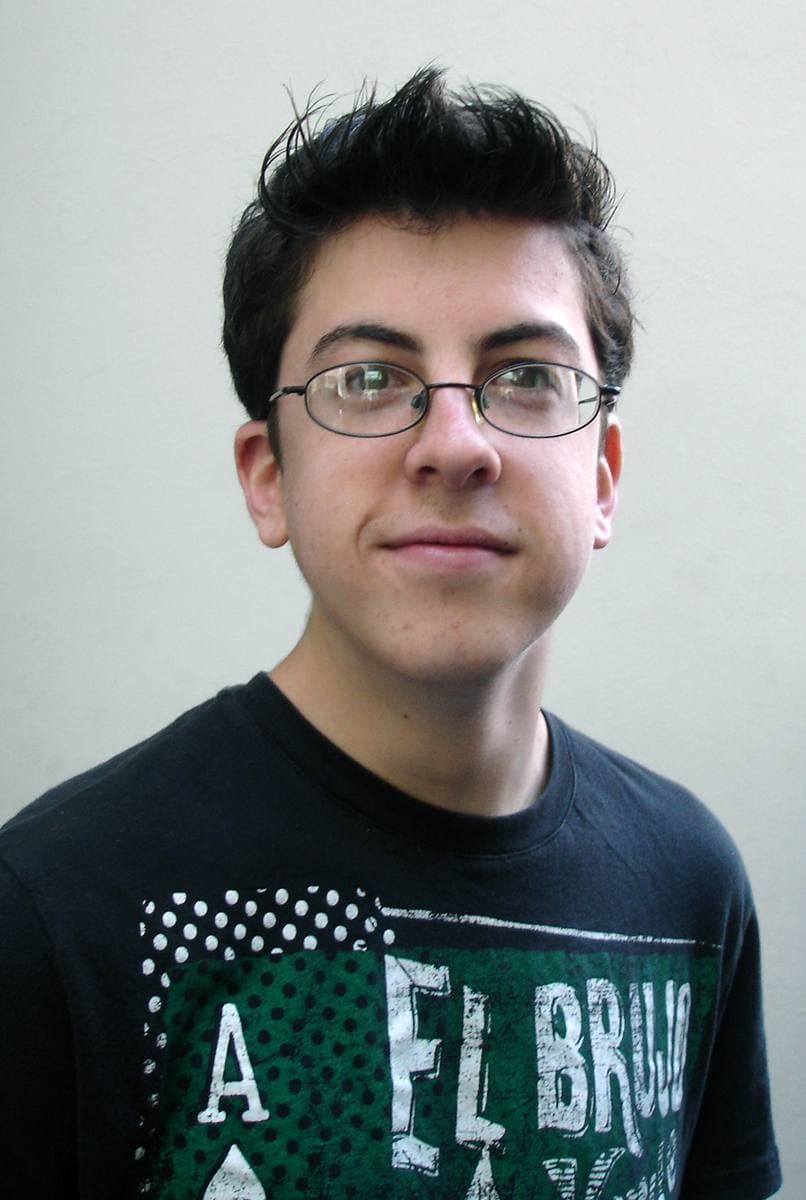 Christopher Mintz-Plasse in glasses and a black T-shirt against a pale wall