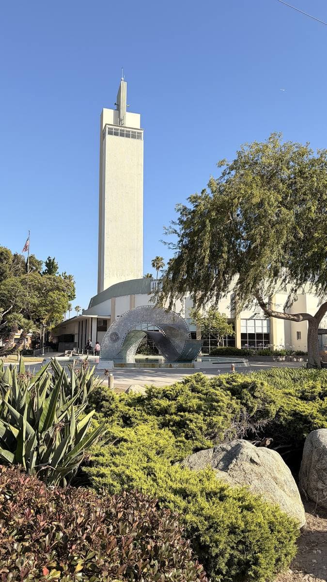 A white tower sculpture rising above shrubs in Culver City