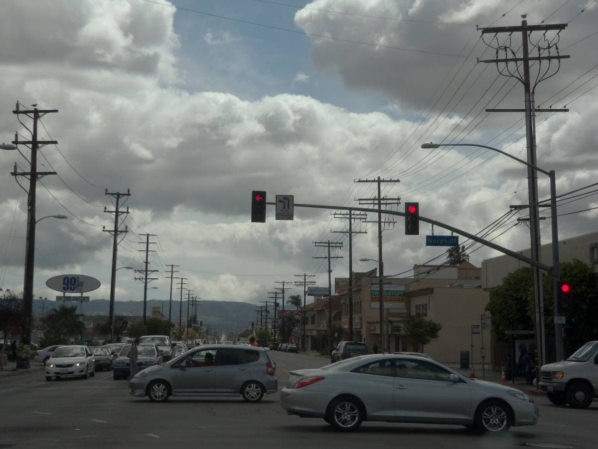 A wide Northridge crossroads with traffic lights, power lines and passing cars
