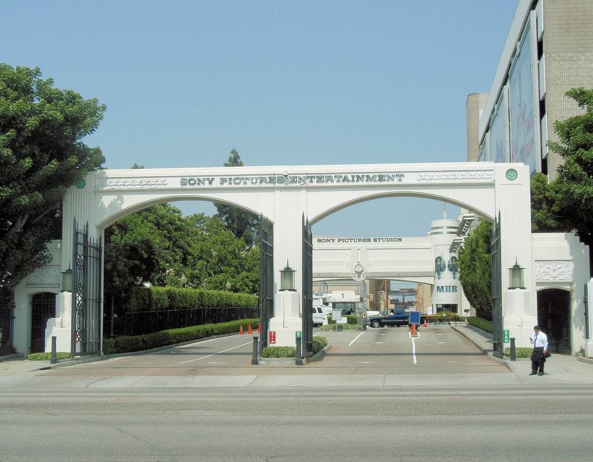 A white arched studio gateway with a road through it