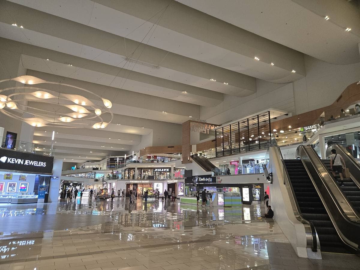 A bright mall atrium with escalators and shopfronts