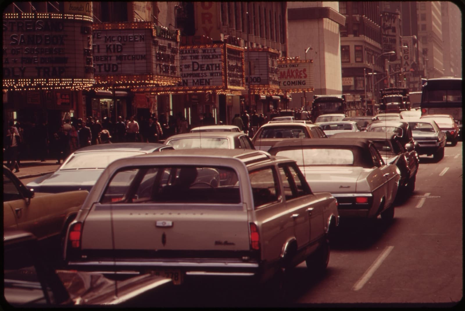 A jam of 1970s cars on 42nd Street under a row of cinema marquees