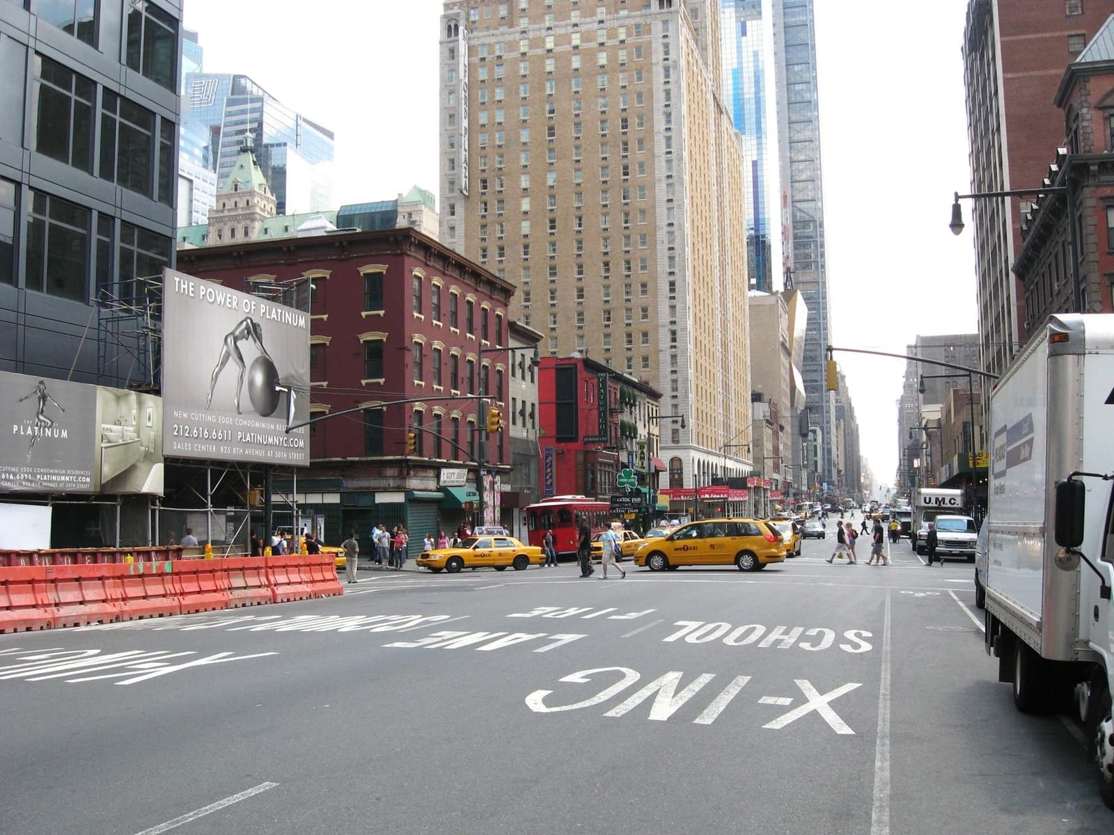 Looking down a wide avenue of mixed old and new buildings, yellow cabs at the lights
