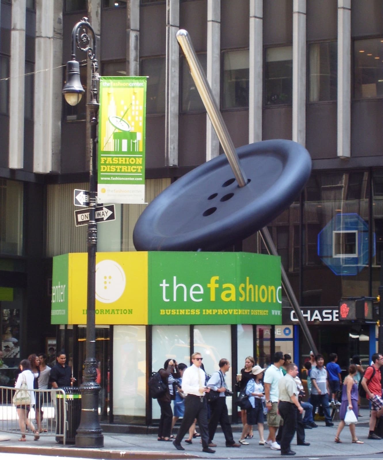 A giant needle threaded through a huge button above a kiosk on Seventh Avenue