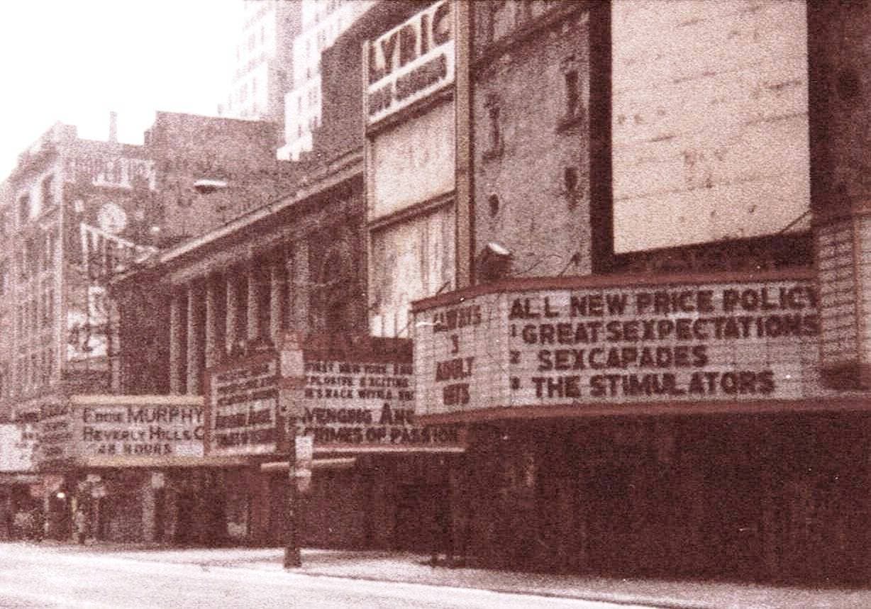 A run-down 42nd Street theatre front with a marquee listing films