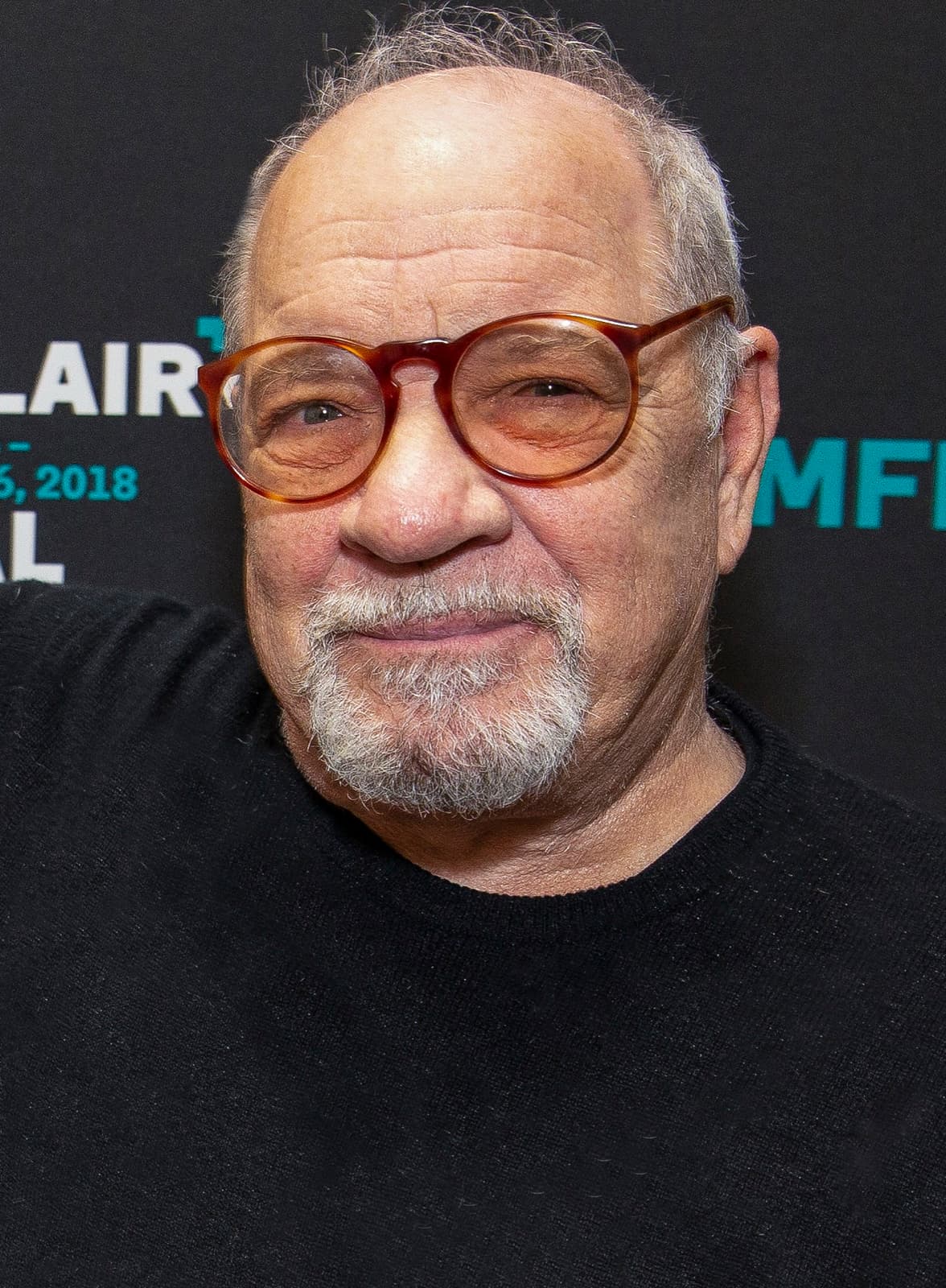 Paul Schrader, grey-bearded in round tortoiseshell glasses and a black jumper
