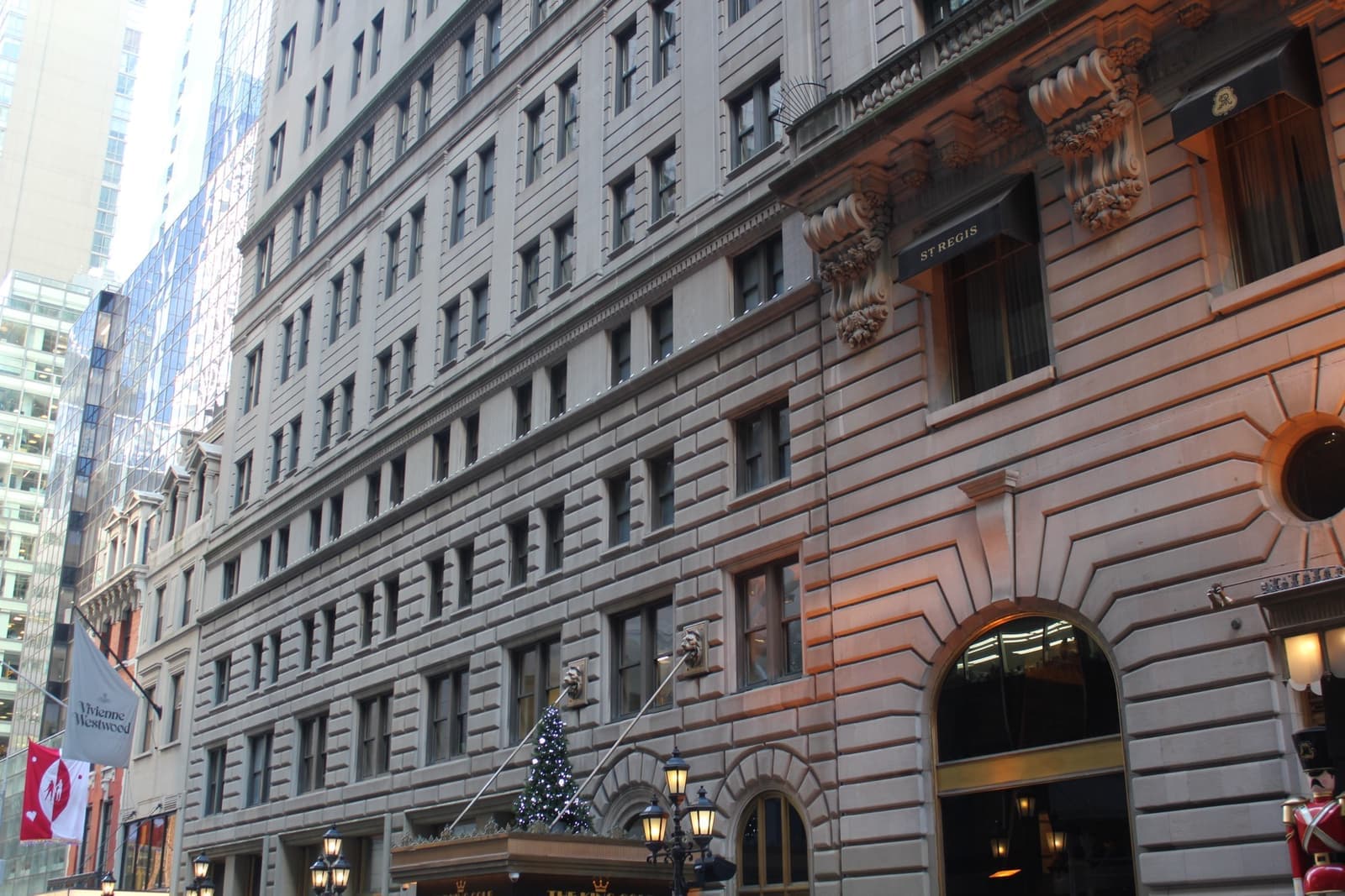 A grand Beaux-Arts hotel front of pale stone with flags and a canopy