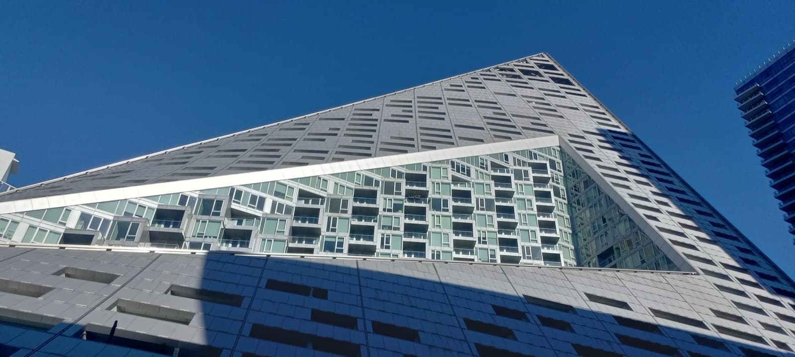A sloping, pyramid-like apartment block with angled steel balconies