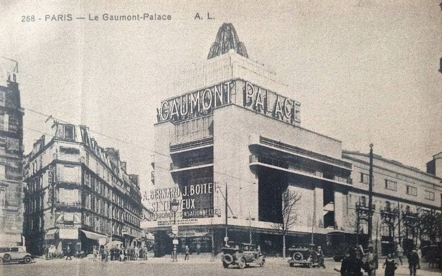 An old postcard of a large modern cinema building with a tall sign