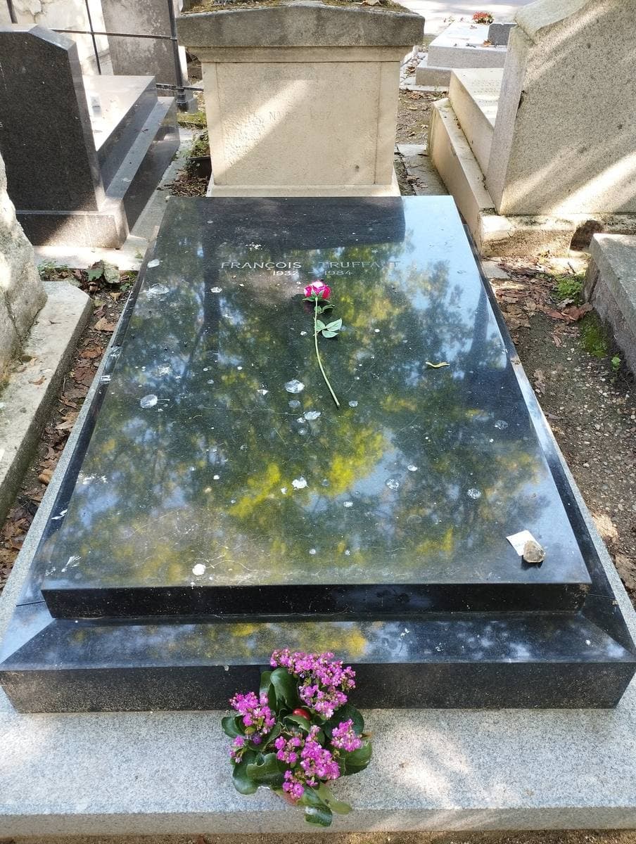 A plain black stone grave with flowers laid on it