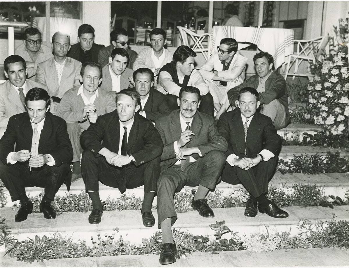 A group of young men in suits sitting on garden steps at night