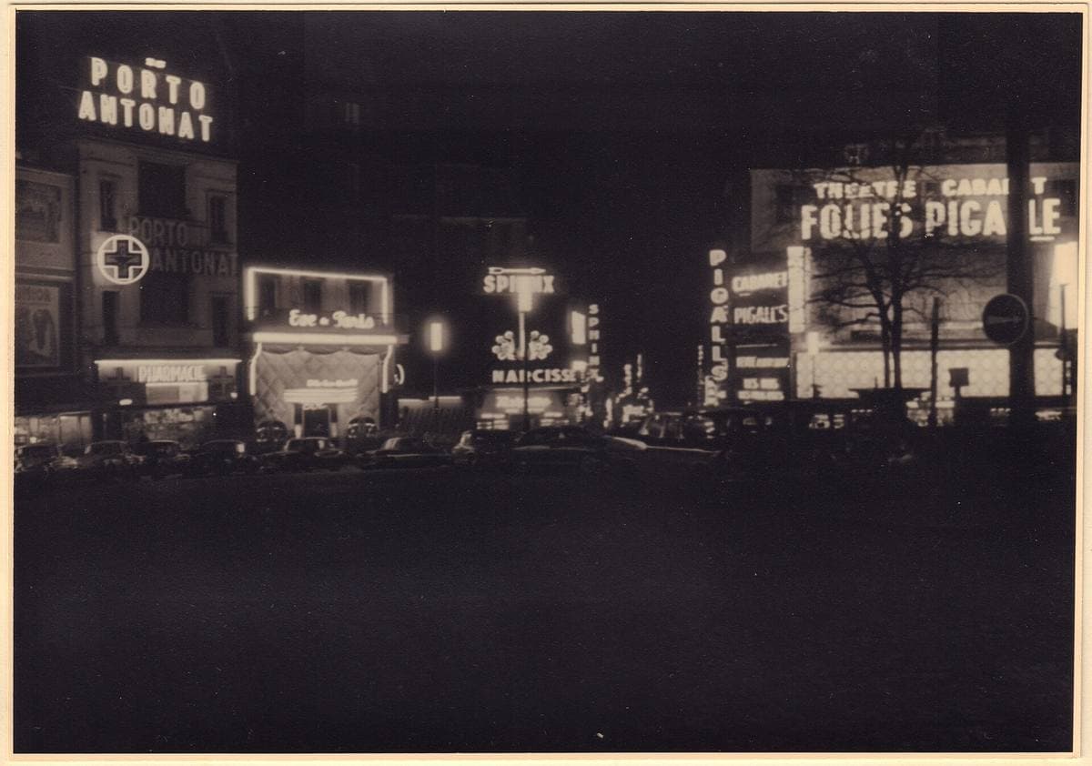 Place Pigalle at night in 1959, neon signs for a cabaret and bars over a dark square