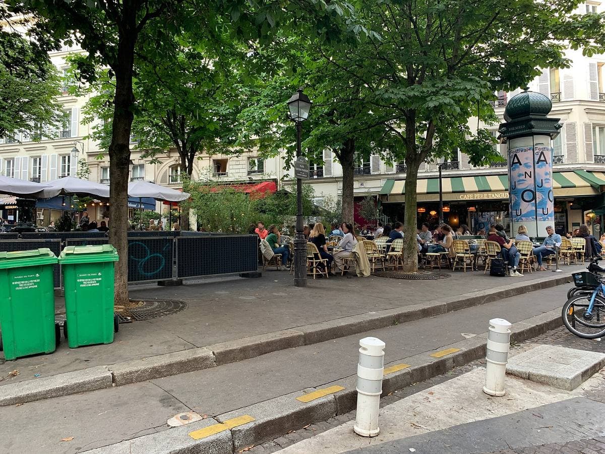 A small square with café terraces under plane trees