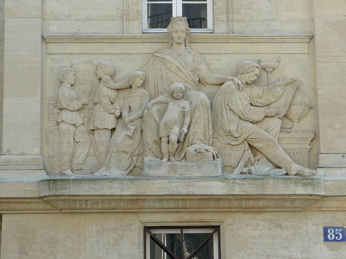 A carved stone panel of a teacher and children