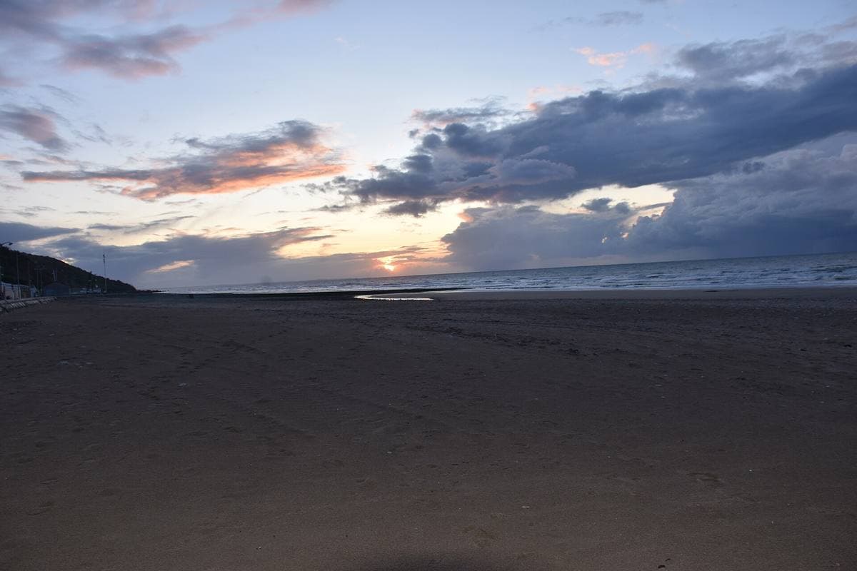 A dark beach under a dusk sky