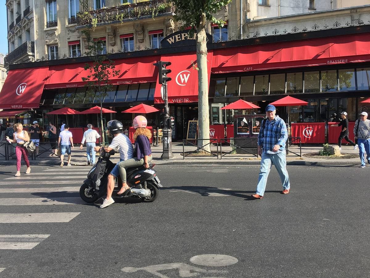 The red awnings of a brasserie on a busy corner