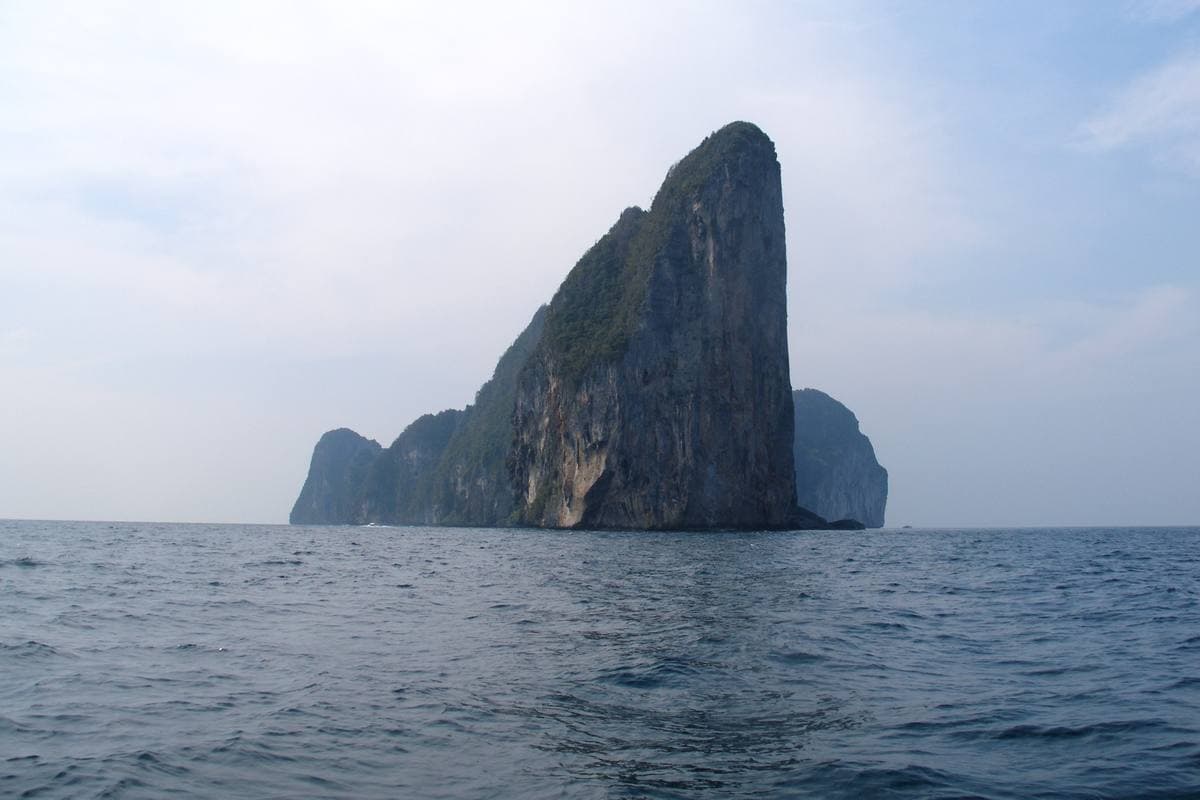 A vertical limestone cliff streaked grey and orange, rising straight out of the sea