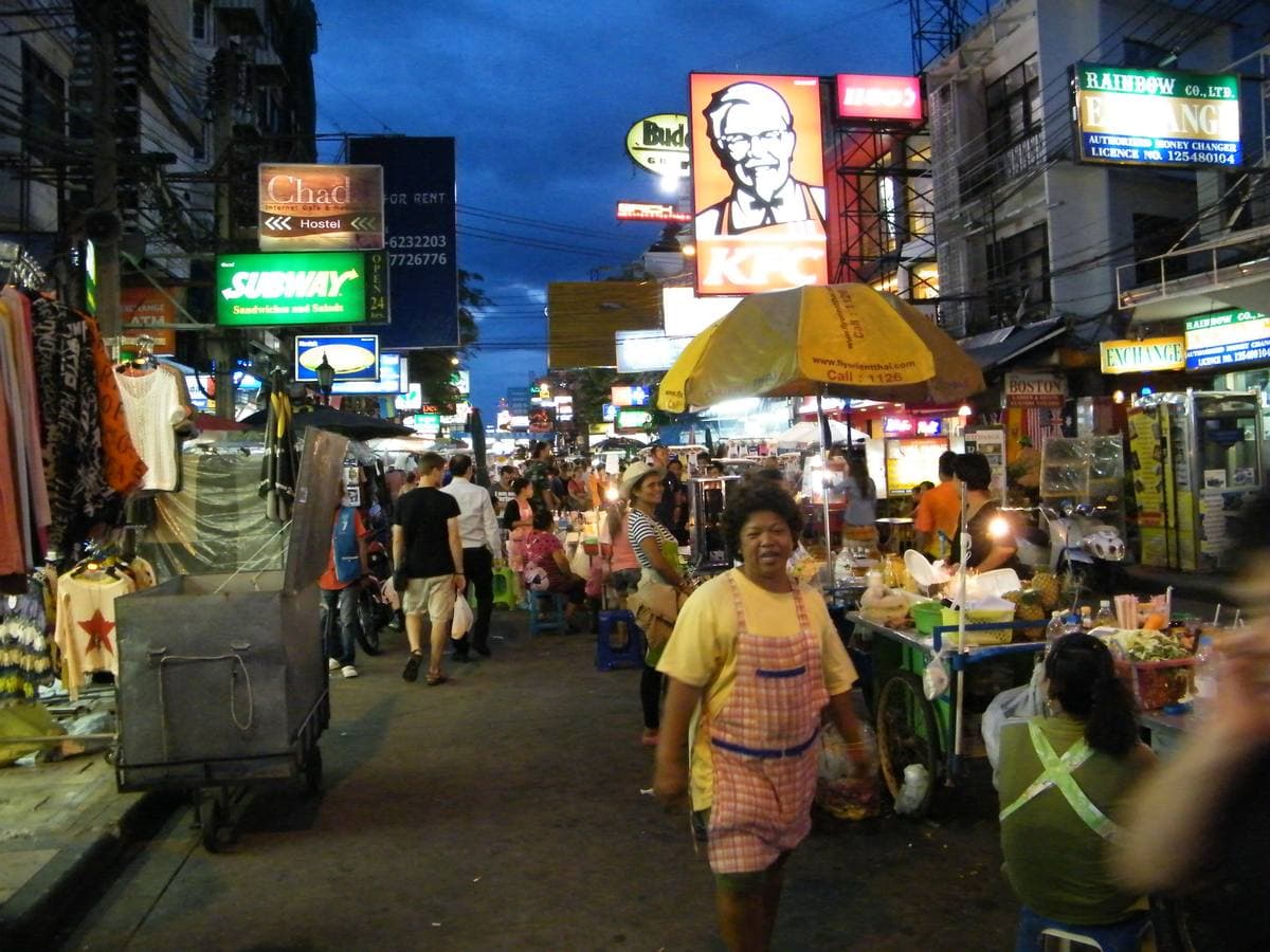 A busy street at night under a canopy of lit signs, crowded with people