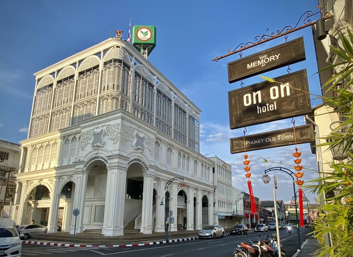 A pale two-storey Sino-Portuguese shophouse front with arched windows next to a bank on a quiet street