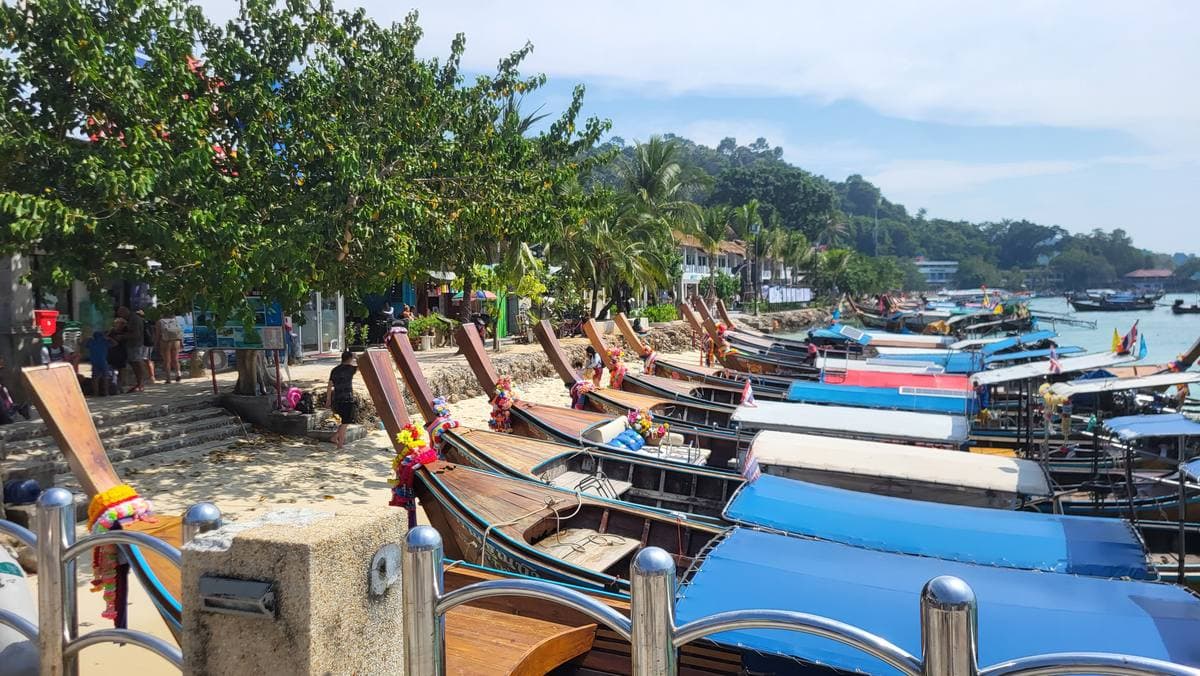 Longtail boats moored in a turquoise bay below green hills on Phi Phi Don