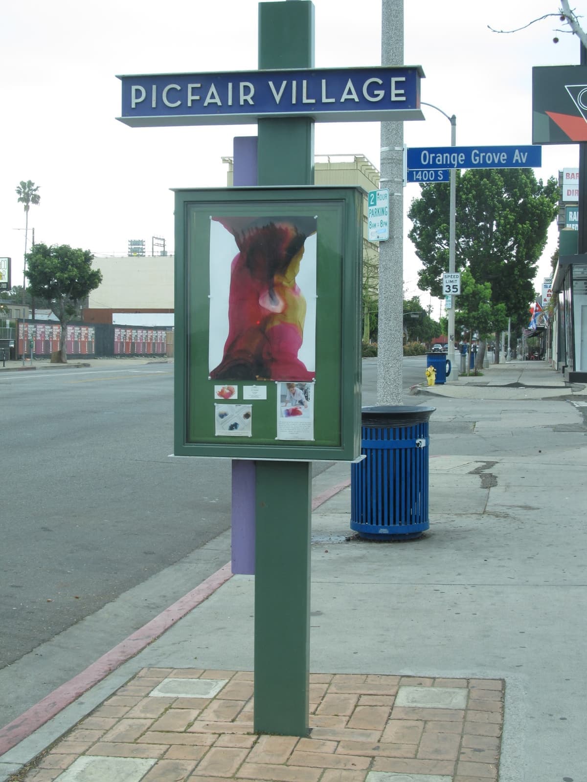 A green street sign reading Picfair Village on Pico Boulevard