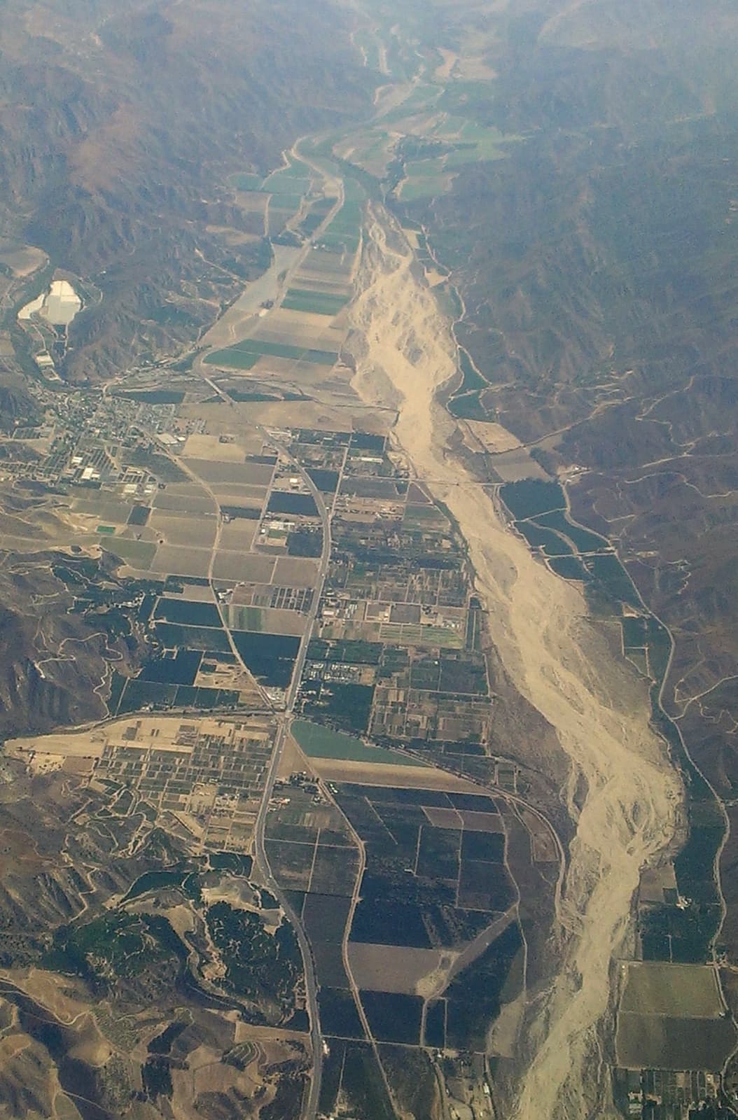 An aerial view of a dry river bed winding past the town of Piru