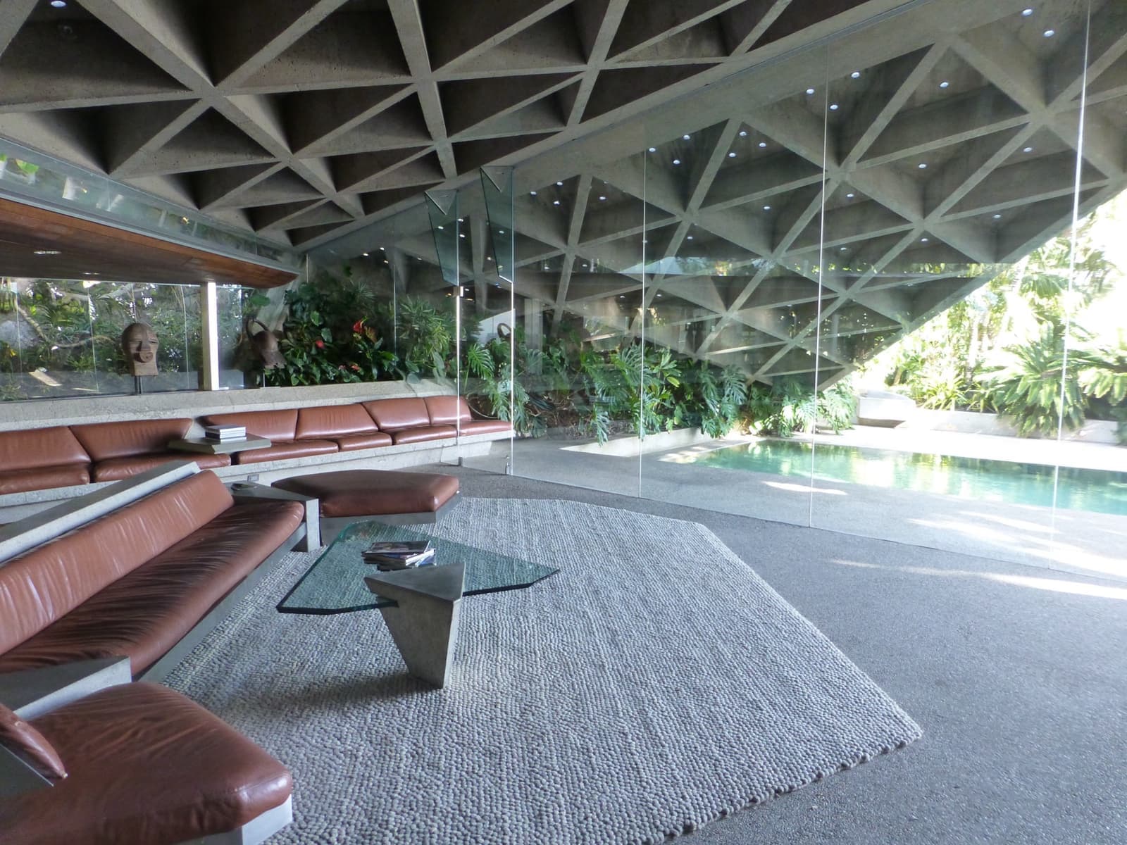 A low concrete coffered ceiling over a sunken living room with glass walls