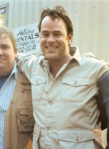 A smiling man with dark hair in a khaki safari shirt