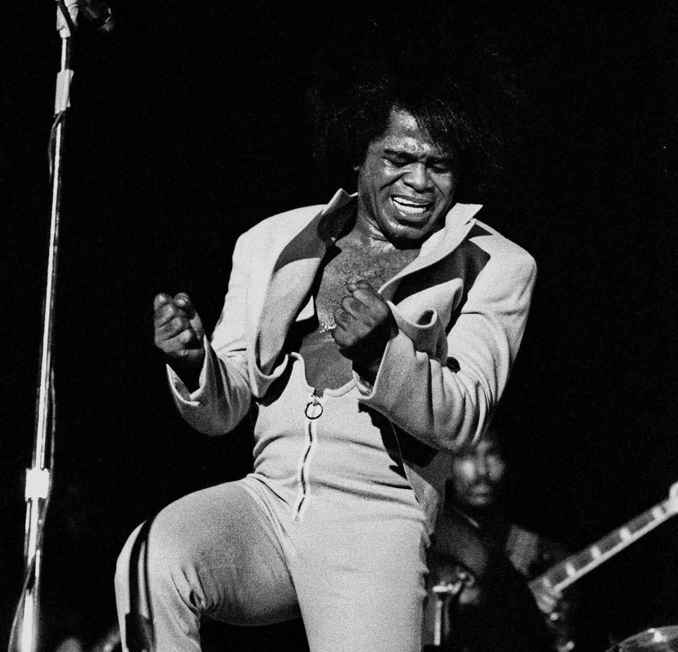 James Brown singing into a microphone on stage