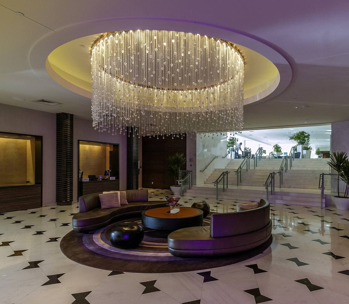 Hotel lobby with a round crystal chandelier and a black-and-white floor