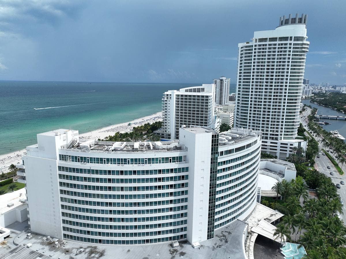 Aerial view of the curved white Fontainebleau hotel beside the ocean