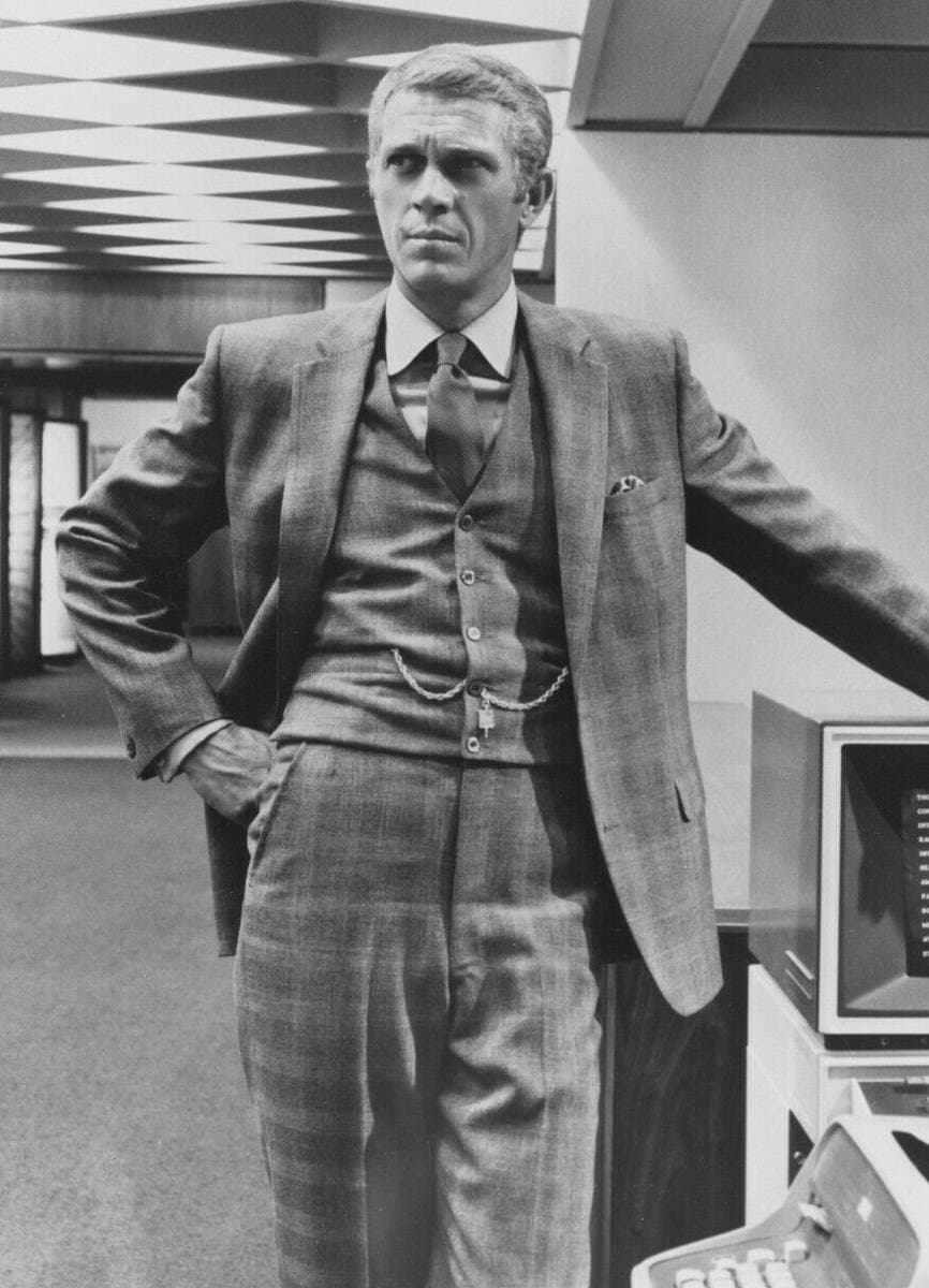 Steve McQueen in a three-piece check suit, one hand on his hip