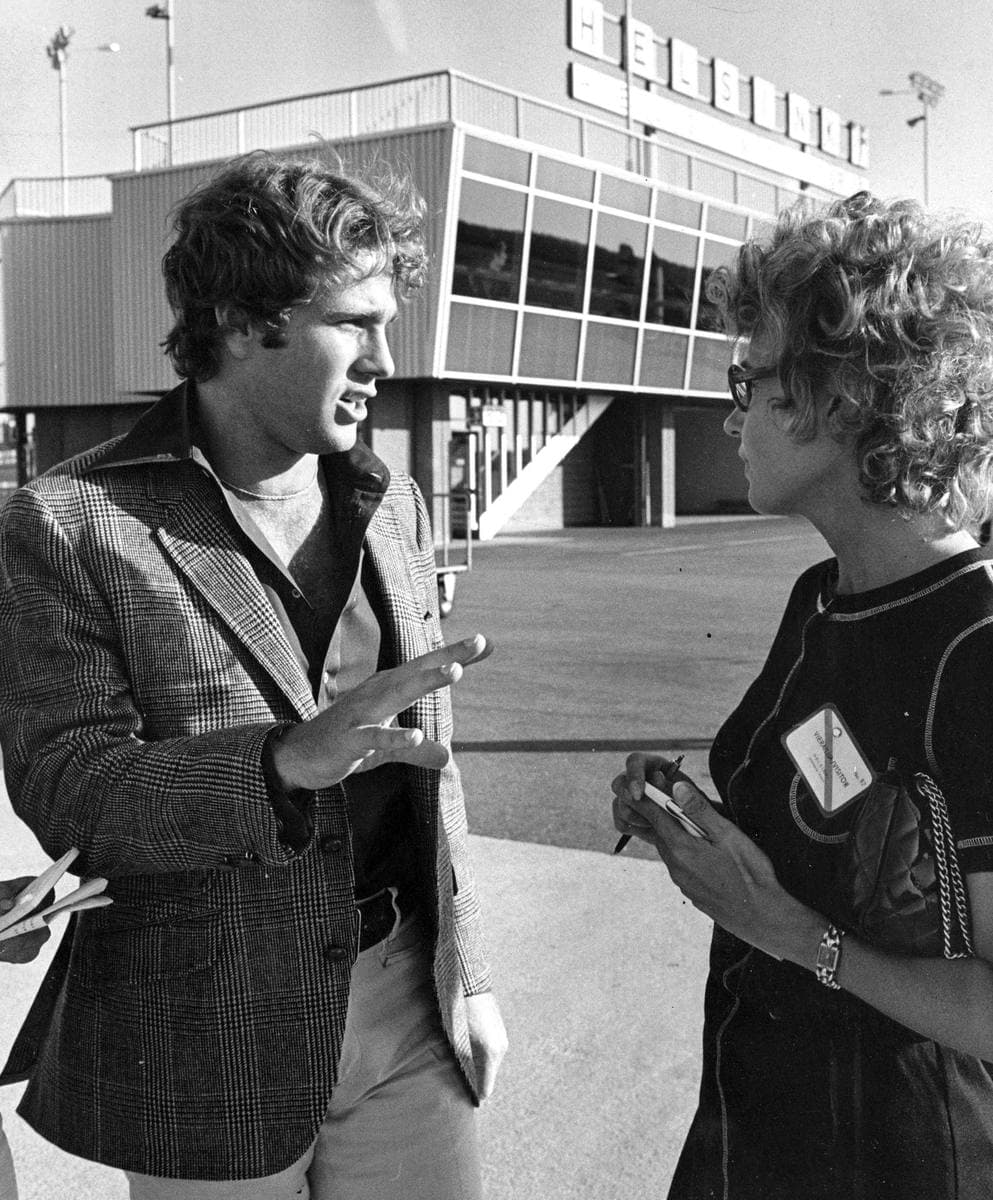 Ryan O’Neal in a jacket talking with a woman outside a building
