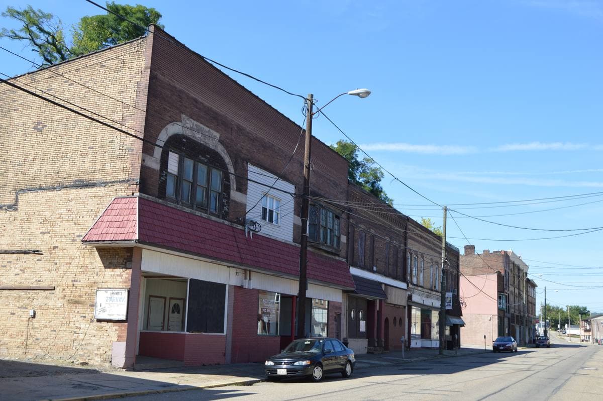 Two- and three-storey brick shopfronts along a quiet main street under a blue sky