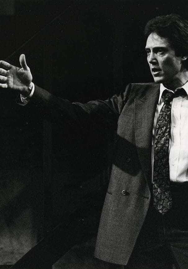 Christopher Walken on stage in a suit, one arm stretched out
