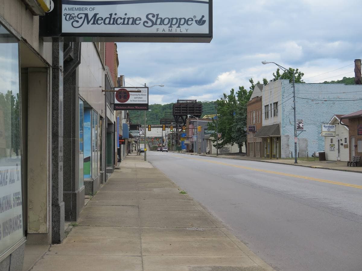 An empty main street with shopfronts and a pharmacy sign