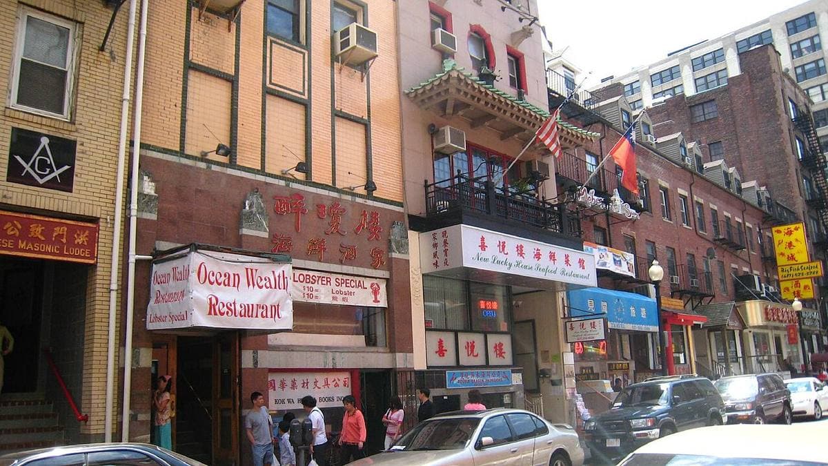 Restaurant signs in Chinese and English along a narrow brick street