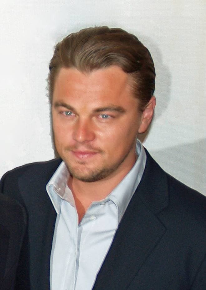 Leonardo DiCaprio in a dark jacket and open-necked shirt, looking to one side
